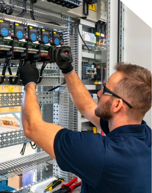 Engineer performing wiring in an industrial control panel for automation systems.