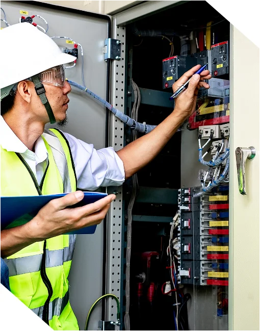 Engineer inspecting an industrial electrical switchgear cabinet for systems maintenance.